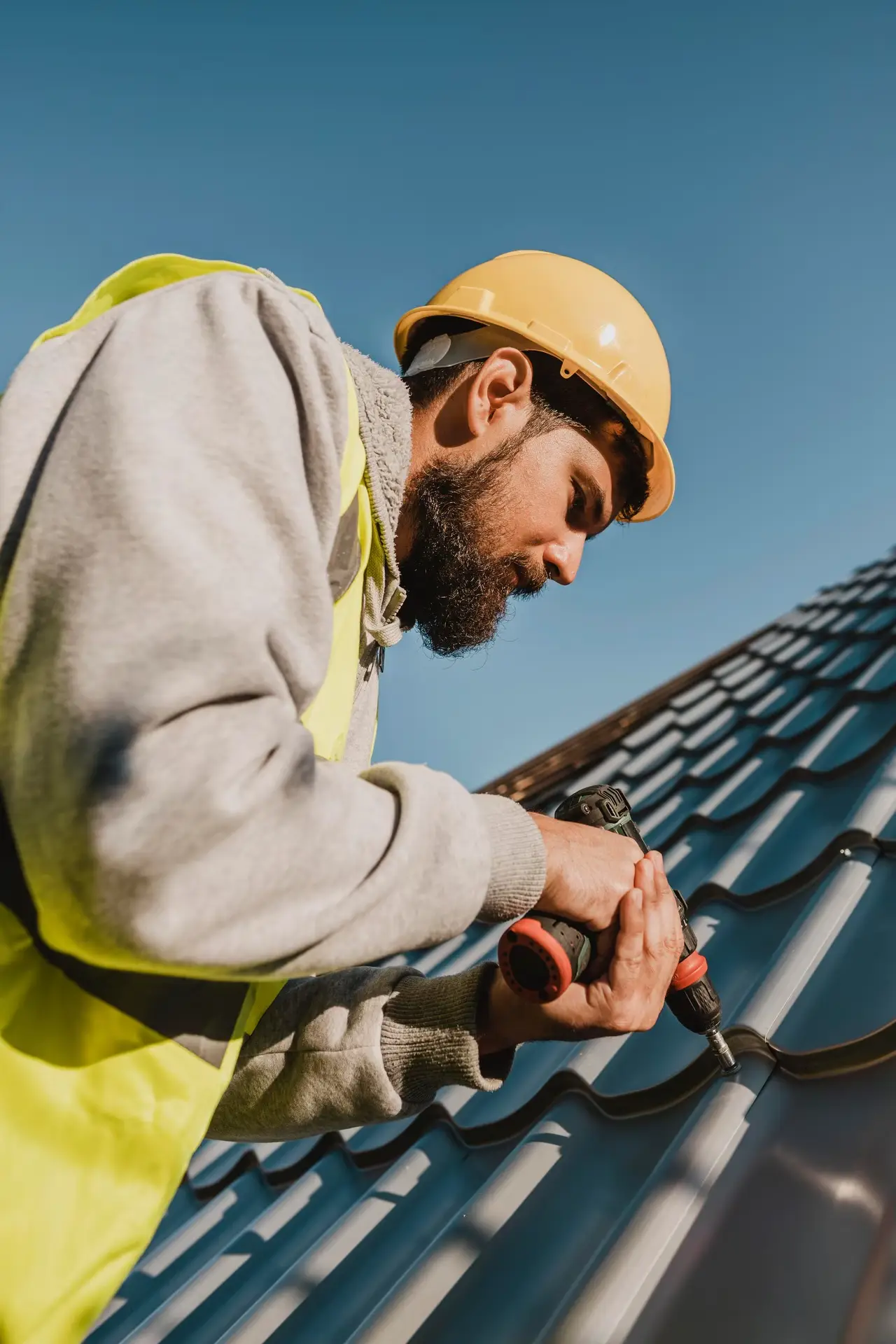 Man working on roof with a drill low view